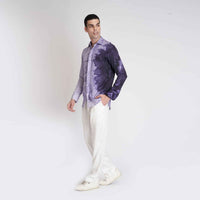 Side profile view of the purple ombre tie-dye shirt with white trousers