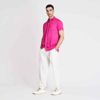 Angled front view of the solid hot pink camp shirt with white trousers