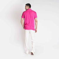 Back view of the solid hot pink camp shirt with white trousers