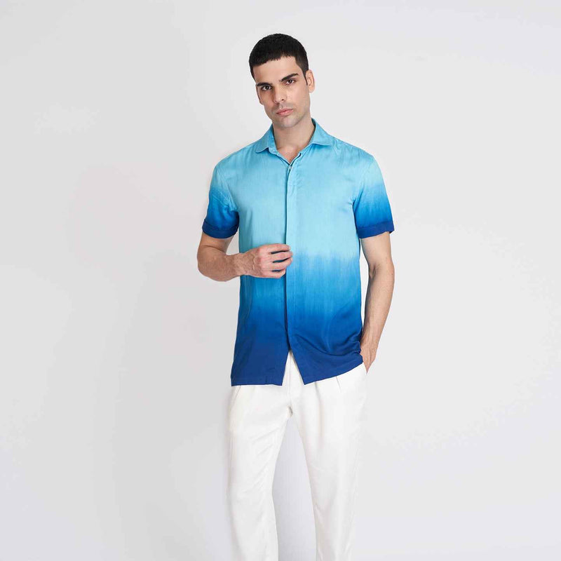 Front view of the blue ombre short-sleeve camp shirt styled with white trousers