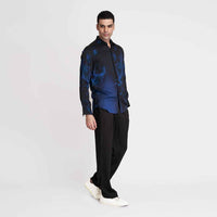 Angled front view of the black and blue tie-dye print shirt with black trousers