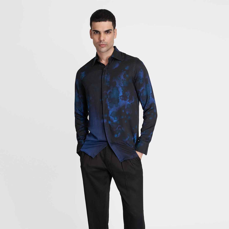 Front view of the black and blue tie-dye print shirt styled with black trousers