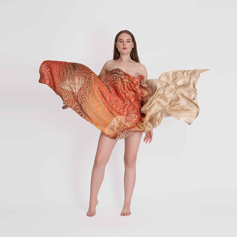 Model wrapped in the orange and gold ombre butterfly print scarf, arms spread