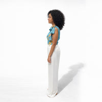 Side profile view of the teal one-shoulder floral top with white wide-leg trousers