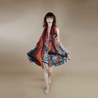 Front view of the orange and blue abstract print scarf worn as a flowing halter dress