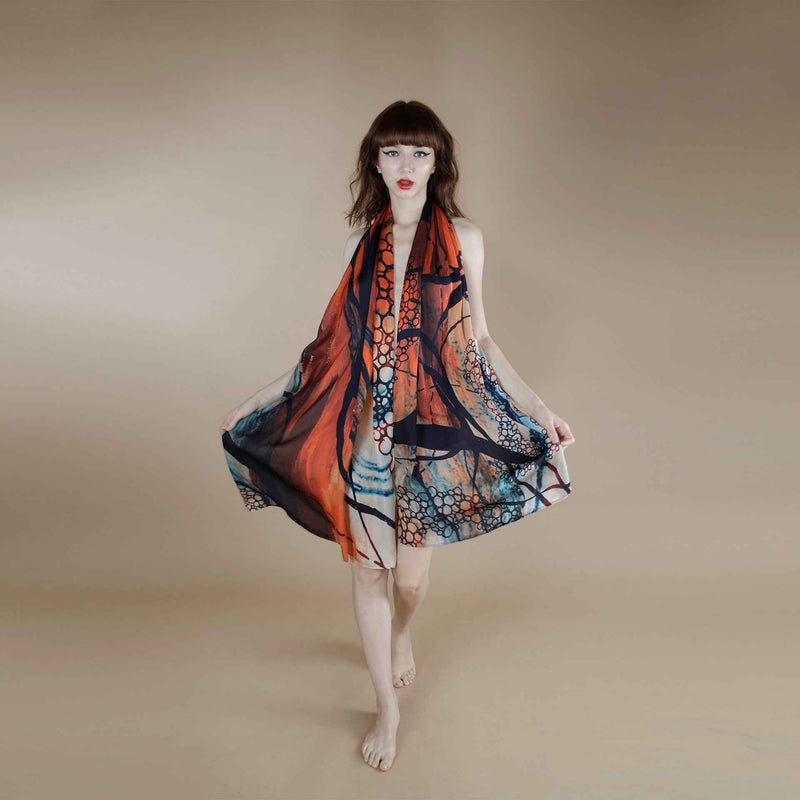 Front view of the orange and blue abstract print scarf worn as a flowing halter dress