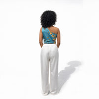 Back view of the teal one-shoulder floral top and white wide-leg trousers
