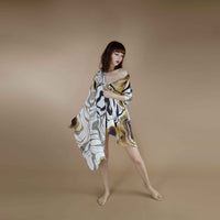 Front view of the grey and gold marbled print scarf worn as an off-shoulder wrap dress