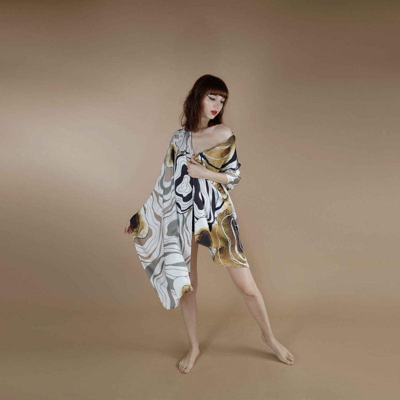 Front view of the grey and gold marbled print scarf worn as an off-shoulder wrap dress