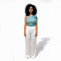 Front view of the teal floral one-shoulder top and white wide-leg trousers, full length