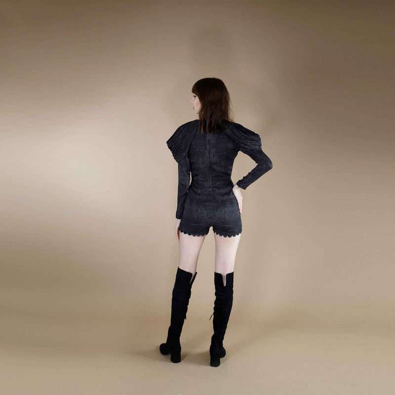 Back view of the black jumpsuit with puff sleeve detail and over-the-knee boots