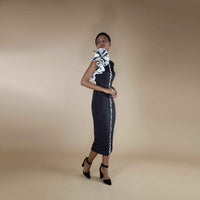 Side view of the black midi dress showing the white trim stripe and rosette shoulder detail