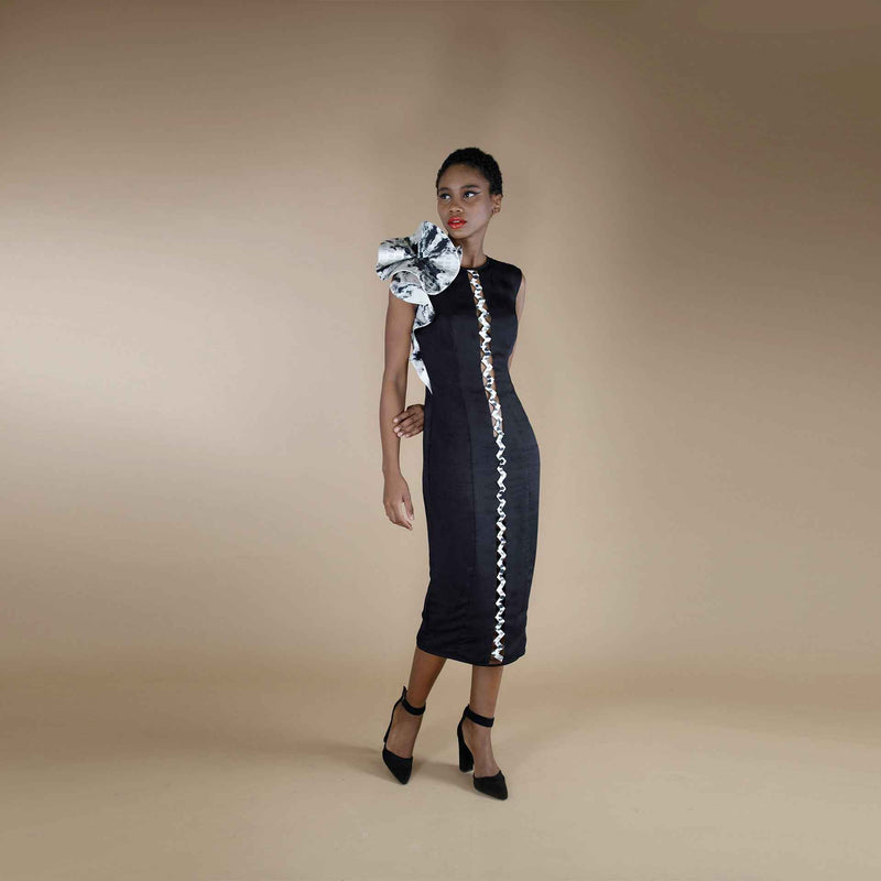 Front view of the black midi dress with a white trim stripe and an oversized rosette shoulder detail