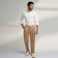 Front view of the beige pleated trousers styled with a white shirt