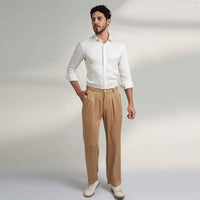 Front view of the beige pleated trousers, full length with a white shirt