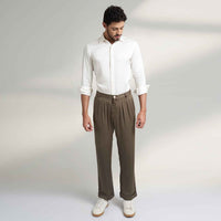 Front view of the olive green pleated trousers, full length with a white shirt