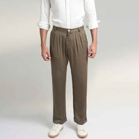 Close-up front view of the olive green pleated trousers showing the waistband and pleat detail