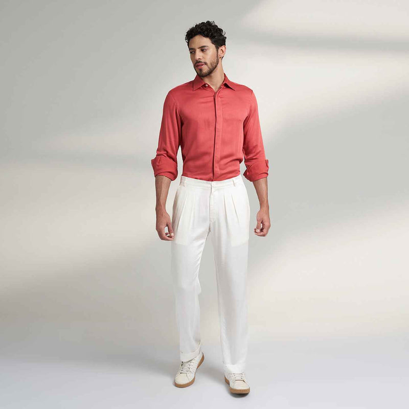 Front view of the off-white pleated trousers styled with a coral shirt