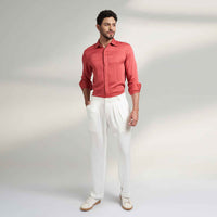 Front view of the off-white pleated trousers, full length with a coral shirt