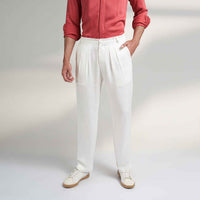 Close-up front view of the off-white pleated trousers showing the waistband and pleat detail