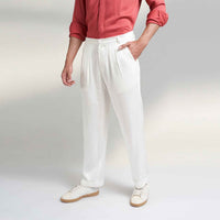 Close-up angled view of the off-white pleated trousers with pocket detail