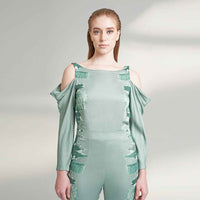 Close-up front view of the sage green jumpsuit showing the cold-shoulder and tonal print detail