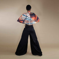 Back view of the orange and black print cape top and black wide-leg trousers