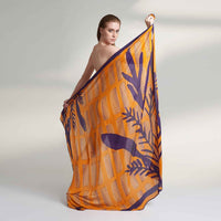Model holding out the orange and purple leaf print scarf, back view