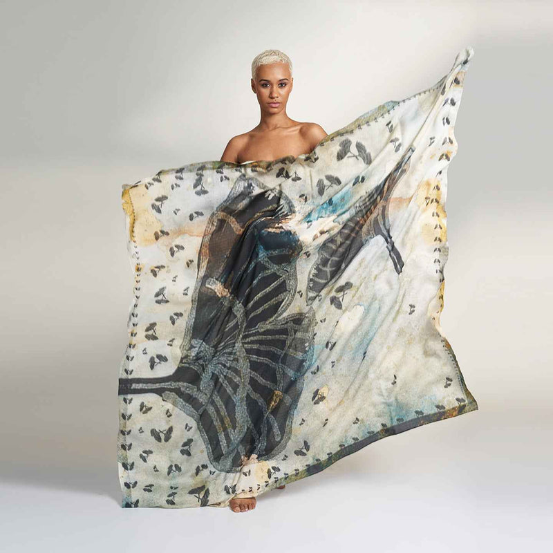 Model holding out the gold and navy butterfly print scarf to show its full spread
