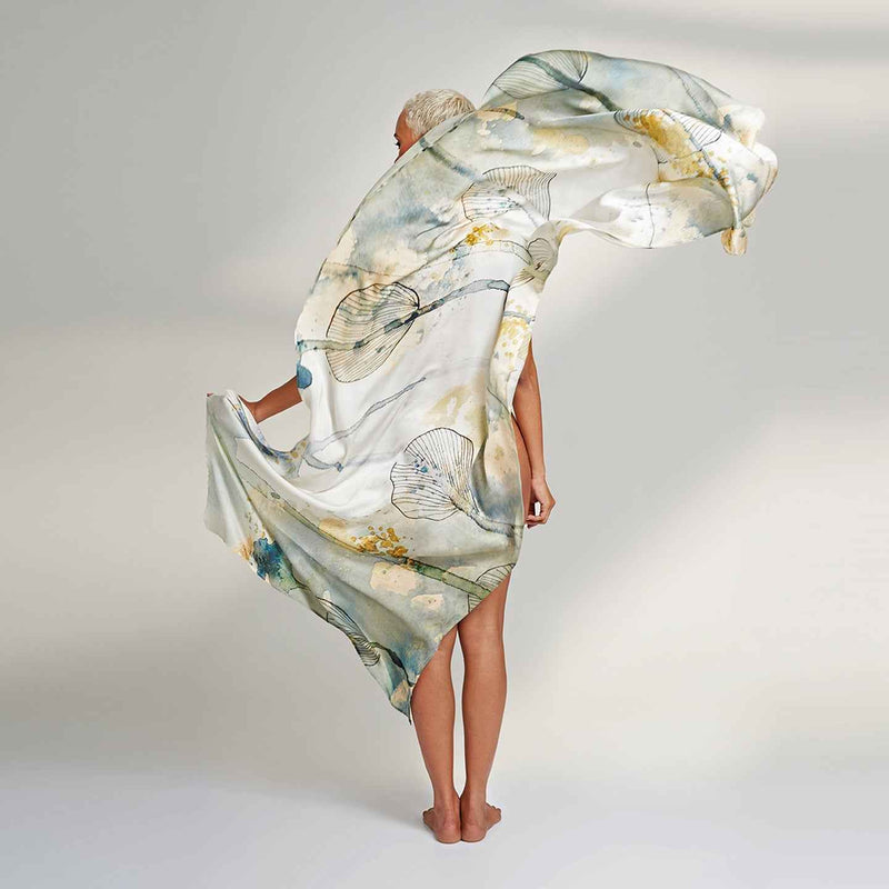 Model wearing the white and yellow watercolor floral print scarf as a flowing wrap dress, back view