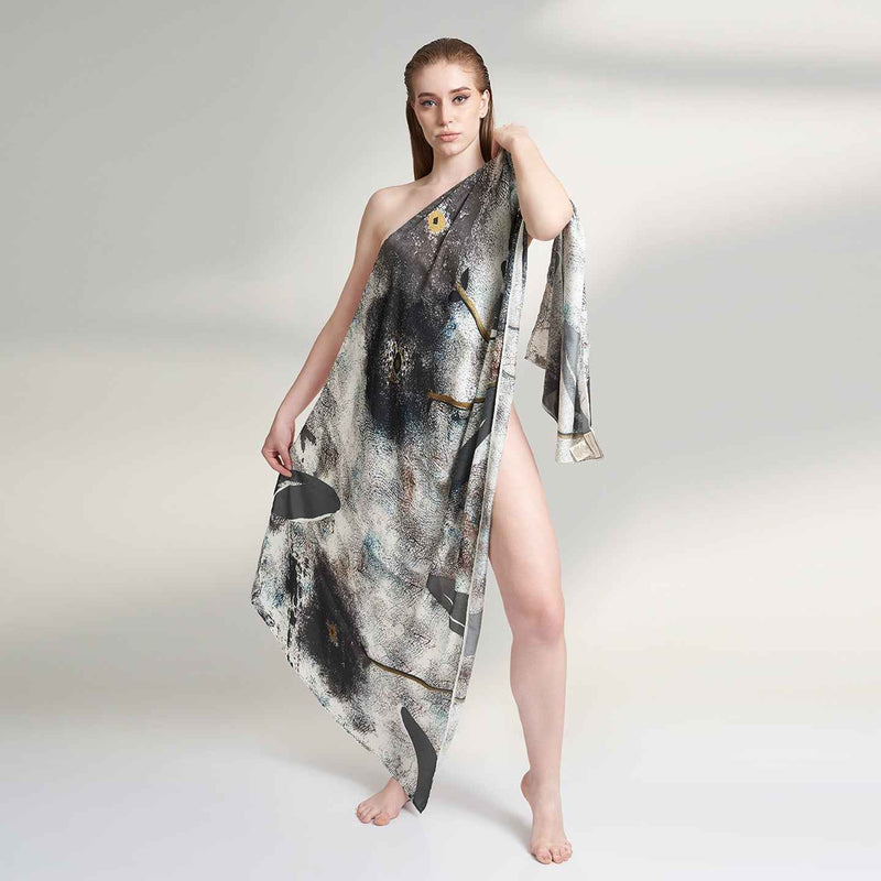 Front view of the model draped in the grey and black abstract print scarf