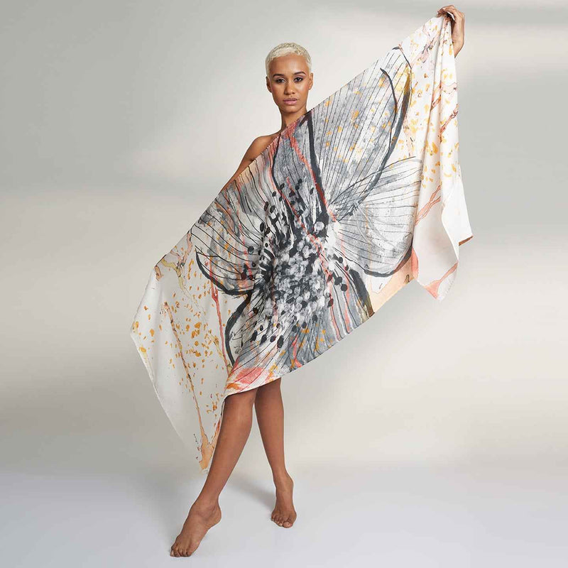 Front view of the model holding out the pink and orange floral drip print scarf
