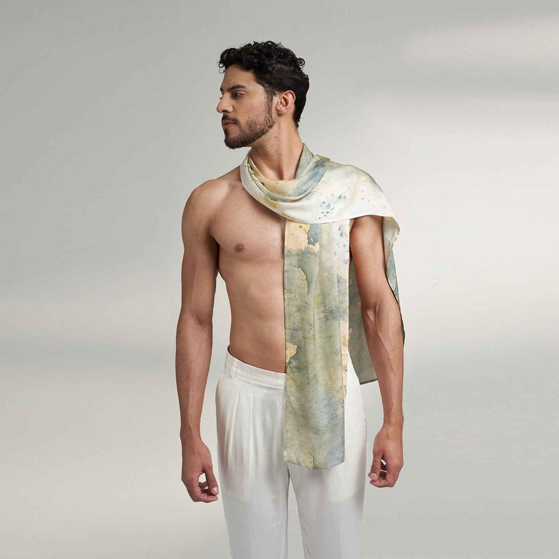 Side view of a man wearing the grey and gold watercolor floral print scarf with white trousers