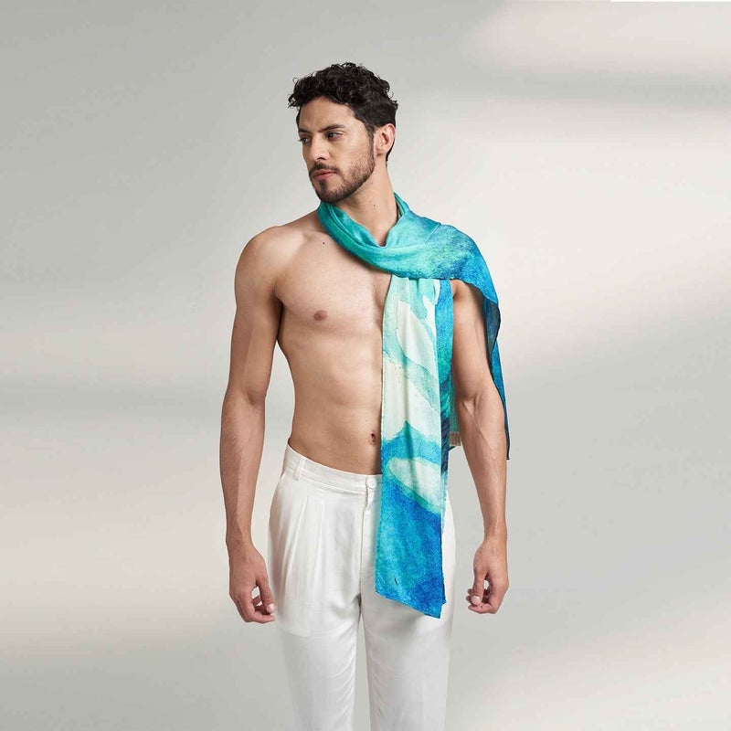 Front view of a man wearing the teal watercolor print scarf with white trousers