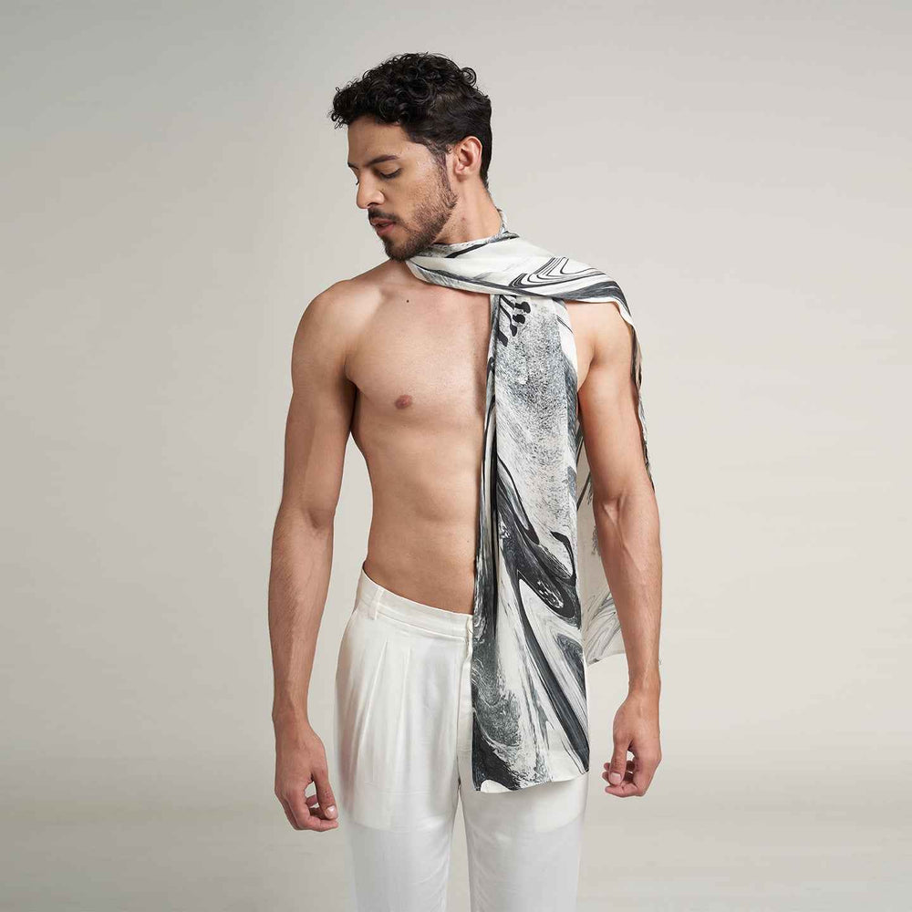 Front view of a man wearing the grey and black marbled print scarf with white trousers