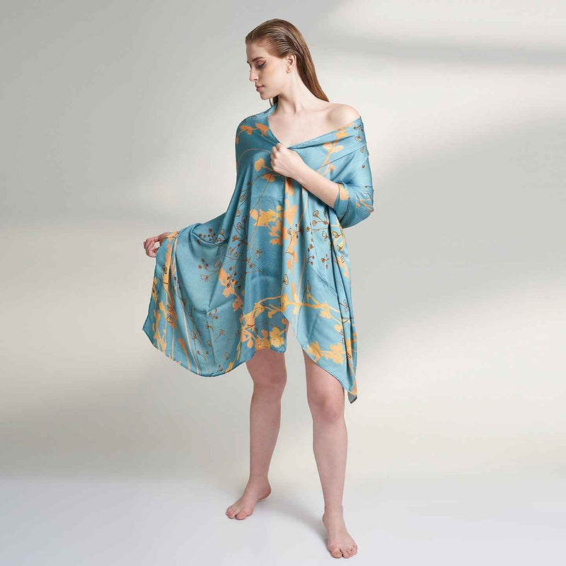 Front view of the model wearing the teal blue and gold branch print scarf as a wrap