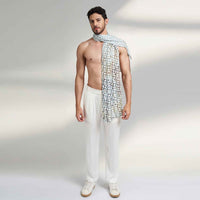 Side view of a man wearing the blue and white geometric floral print scarf with white trousers