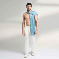 Side view of a man wearing the solid teal scarf with white trousers