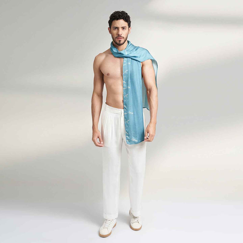 Side view of a man wearing the solid teal scarf with white trousers