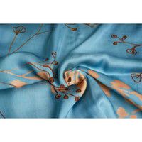 Close-up of the teal blue and gold branch print scarf fabric, gathered