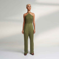 Angled front view of the olive green jumpsuit with a smocked halter neckline