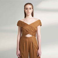 Close-up front view of the camel brown jumpsuit showing the off-shoulder wrap and waist cutout detail