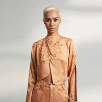 Close-up front view of the peach branch print draped jacket top, styled with matching trousers