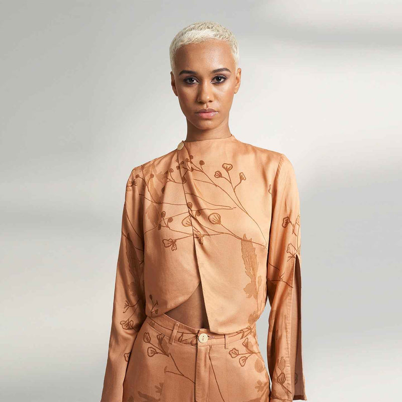 Close-up front view of the peach branch print draped jacket top, styled with matching trousers