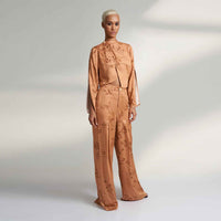 Angled side view of the peach branch print jacket top and wide-leg trousers