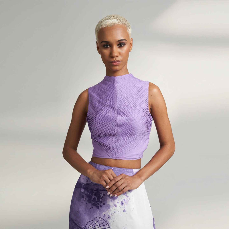 Front view of the pleated lilac purple crop top, styled with a purple and white print skirt