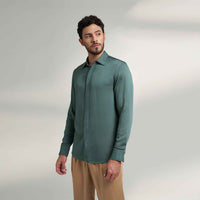 Angled front view of the solid sage green shirt styled with khaki trousers
