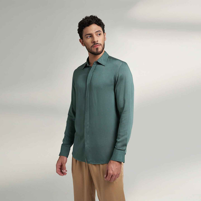 Angled front view of the solid sage green shirt styled with khaki trousers
