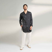 Front view of the longline black and grey tonal print shirt and white trousers