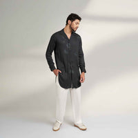 Side view of the longline black and grey tonal print shirt with white trousers